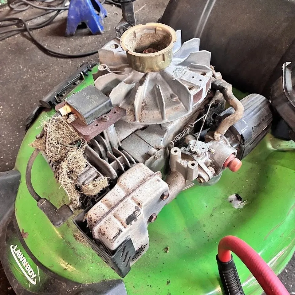 Lawn-Boy mower engine with the shroud off, packed with old grass